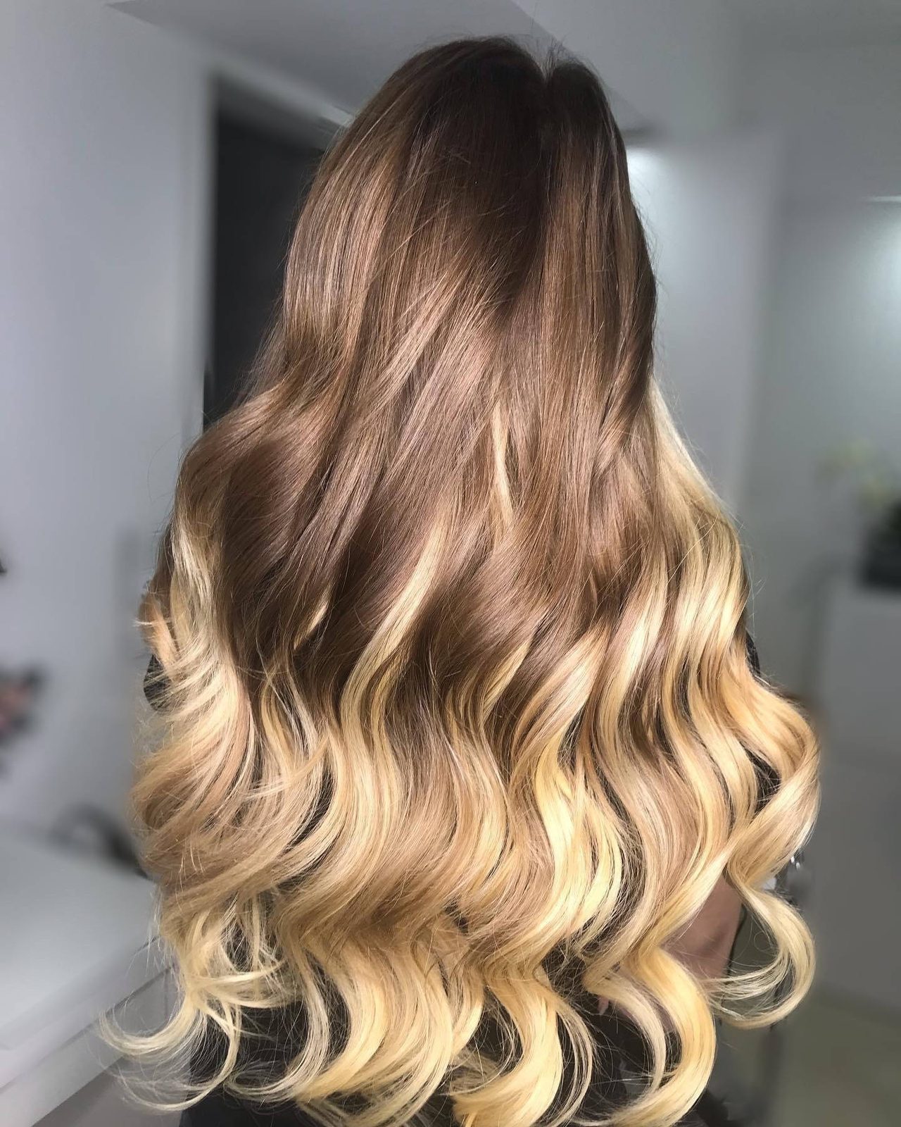 Lange, gewellte Balayage in Braun und Honigblond, von hinten fotografiert